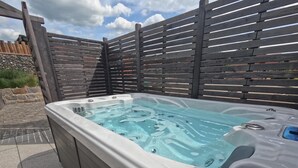 A hot tub with a wooden deck and stone wall in the background. - Crab on the Rhön beach with whirlpool (Wartmannsroth)