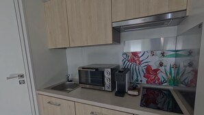 A compact kitchen with wooden cabinets, a toaster, a kettle, and a microwave. - Crab on the Rhön beach with whirlpool (Wartmannsroth)