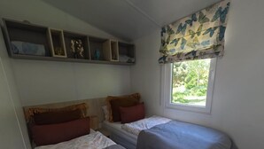 A small, cozy room with two single beds, a window with a butterfly curtain, and a shelf with decorative items. - Crab on the Rhön beach with whirlpool (Wartmannsroth)