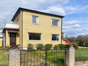 Ein zweistöckiges Backsteinhhaus mit flachem Dach, der Hausnummer '33' und einem eingezäunten Garten.