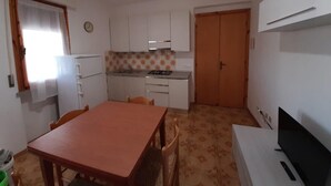 A compact kitchen with white cabinets, a dining table, and a TV.