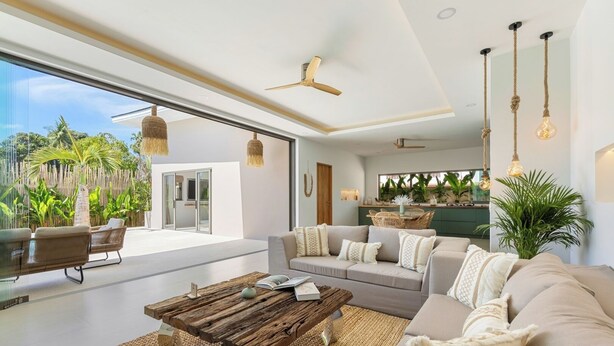 Un salon moderne doté d’un grand canapé, d’une table basse et d’un coin repas offrant une vue sur l’extérieur.