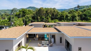 Une maison moderne dotée d’une piscine, de plusieurs niveaux et offrant une vue sur la verdure environnante.