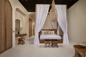 A bedroom with a canopy bed, wooden furniture, and a large mirror.