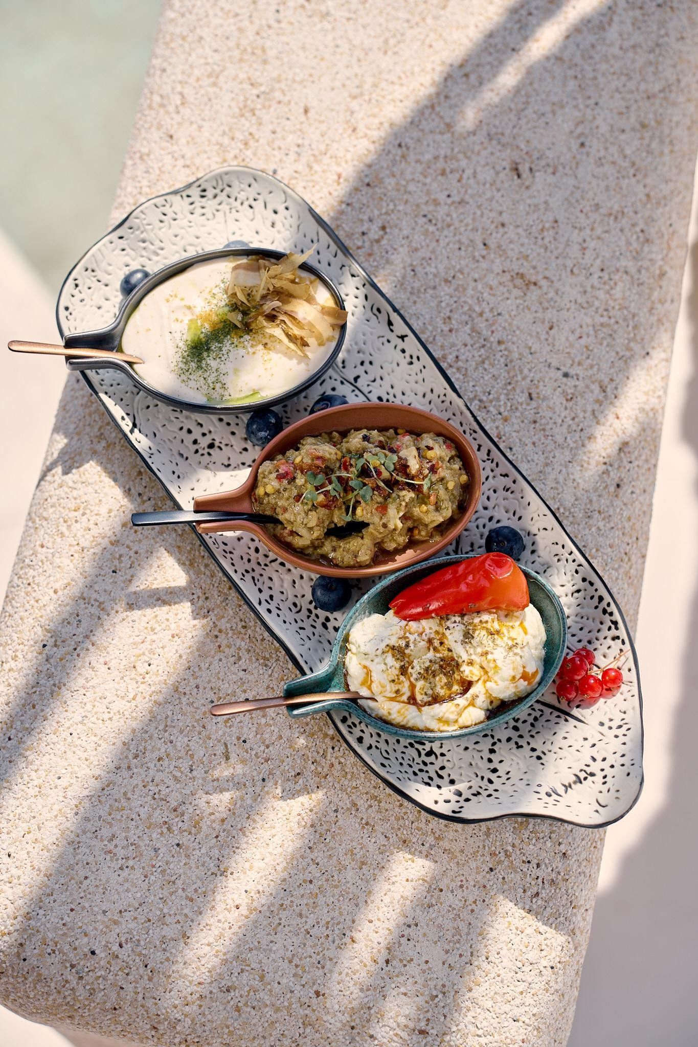 Three dishes on a speckled ceramic serving tray.