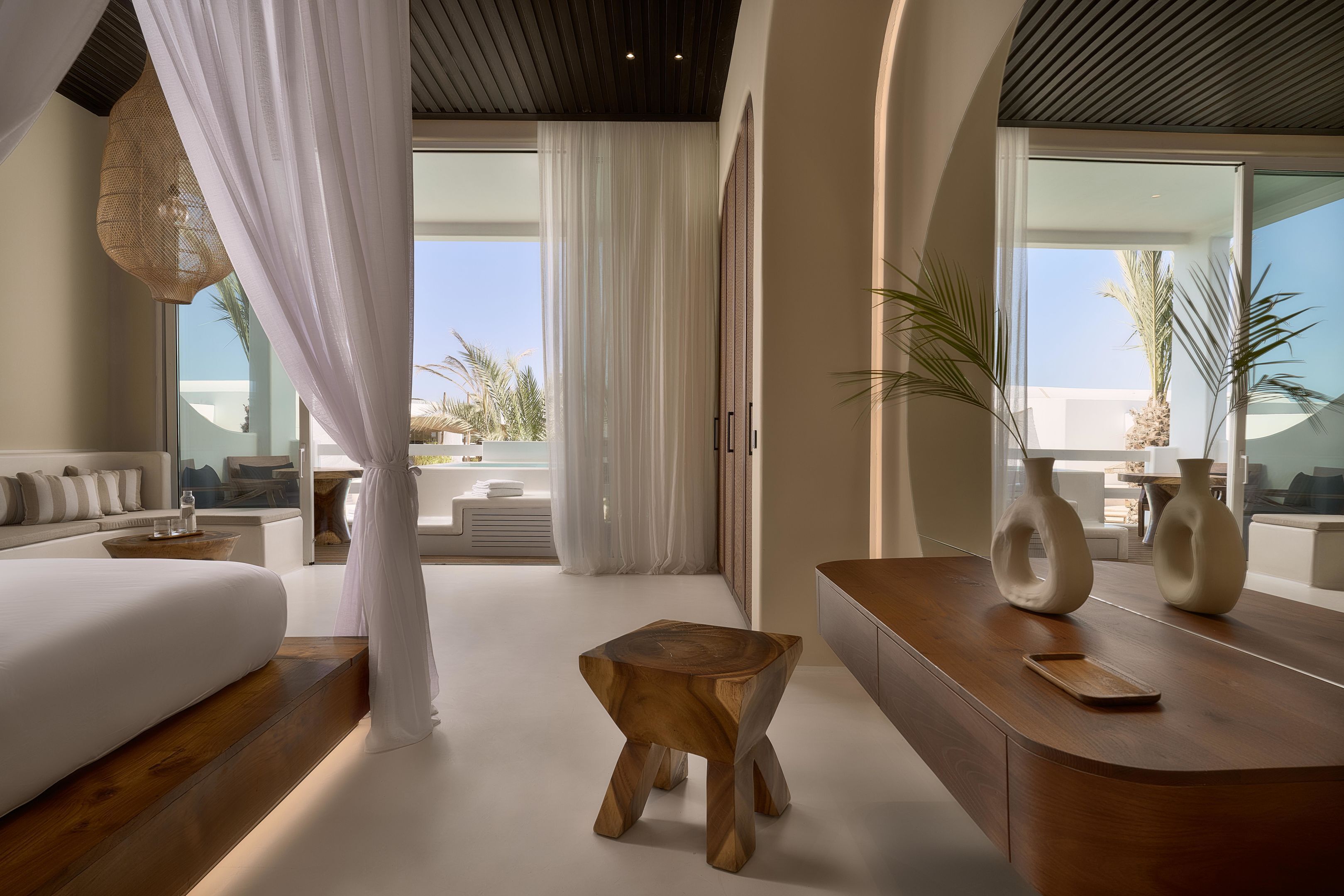 A modern bedroom with a bed, bedside table, and a view of the outdoors.