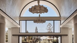 A spacious room with a large arched window, a chandelier, and a red sports car. - Aya Resort (Ayia Napa)