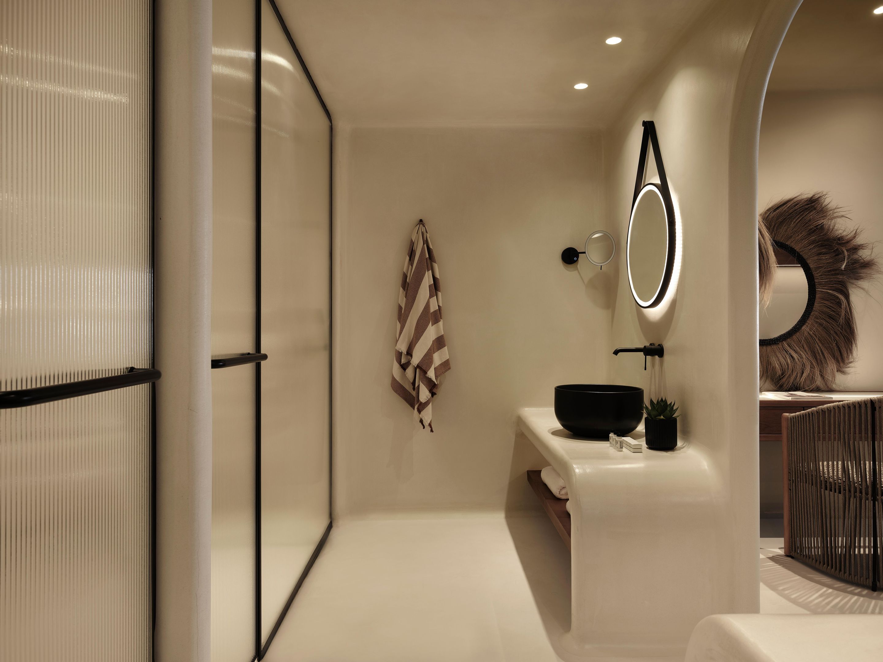 A modern bathroom with a large mirror, a black basin, and a towel rack.