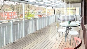 A covered outdoor area with a wooden deck, white railings, and a table with chairs. - 4 Star Holiday Home in Ljusne (Ljusne)