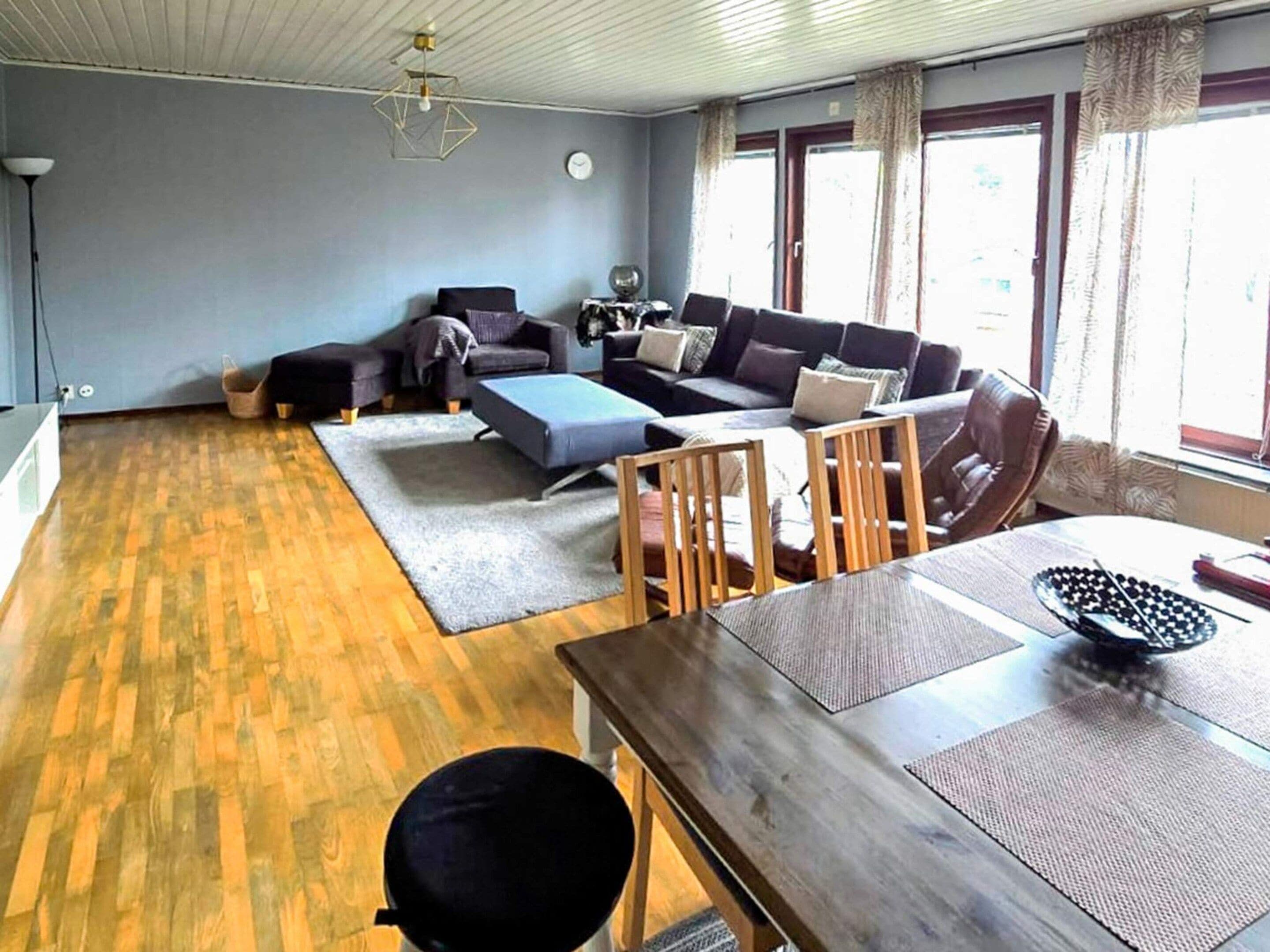A living room with a sofa set, a dining table, and a kitchen area.