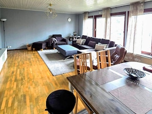 A living room with a sofa set, a dining table, and a kitchen area. - 4 Star Holiday Home in Ljusne (Ljusne)