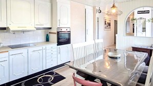 A modern kitchen with white cabinets, a stainless steel oven, and a dining area with a glass table and chairs. - 4 Star Holiday Home in Ljusne (Ljusne)