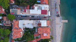 An aerial view of a coastal area with buildings, a beach, and a pier. - Miniq 101 - Near Sea & Foça Center Stone House (Izmir)