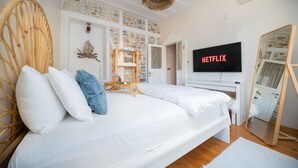 A bedroom with a large bed, a wooden chair, a TV displaying 'NETFLIX', and a stone wall. - Miniq 101 - Near Sea & Foça Center Stone House (Izmir)