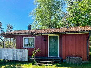 A red wooden cabin with a tiled roof, a green door, and a small porch. - 4 Star Holiday Home in Ed (Ed)