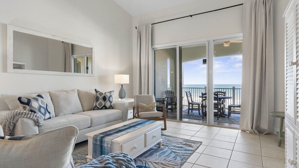 A modern living room with a sofa, armchairs, a coffee table, and a view of the balcony. - Renovated top floor direct oceanfront penthouse Cinnamon Beach condo 862! (Palm Coast)
