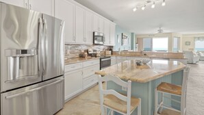 A modern kitchen with stainless steel appliances, white cabinetry, and a large island with bar stools.
