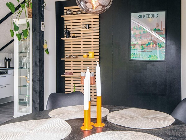 A modern dining area with a wooden slat wall, a framed cityscape poster, and a table set with placemats and candles. - 5 Person Holiday Home in Silkeborg (Silkeborg)