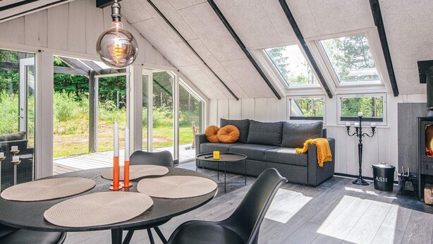 Un espace de vie moderne de style loft, comprenant un grand canapé, une table à manger et des chaises. On y trouve également une cheminée et une grande fenêtre qui laisse entrer la lumière naturelle.