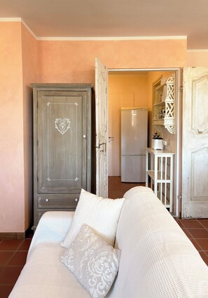 Una habitación con cama, armario, zona de cocina y puerta abierta que da a otra estancia.