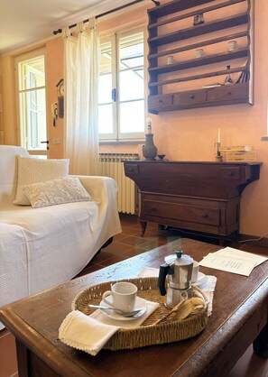 Una habitación acogedora con cama, una mesa de madera con bandeja, un radiador y una ventana con cortinas.