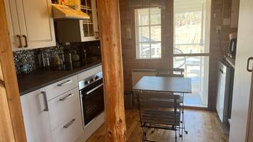 A kitchen with white cabinets, a black countertop, and a wooden table with a metal bench.