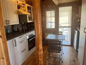 A kitchen with white cabinets, a black countertop, and a wooden table with a metal bench. - 4 Star Holiday Home in Kil (Kil)