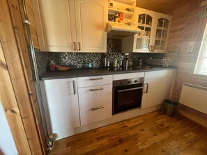 A kitchen with white cabinets, a black oven, and a wooden floor. - 4 Star Holiday Home in Kil (Kil)