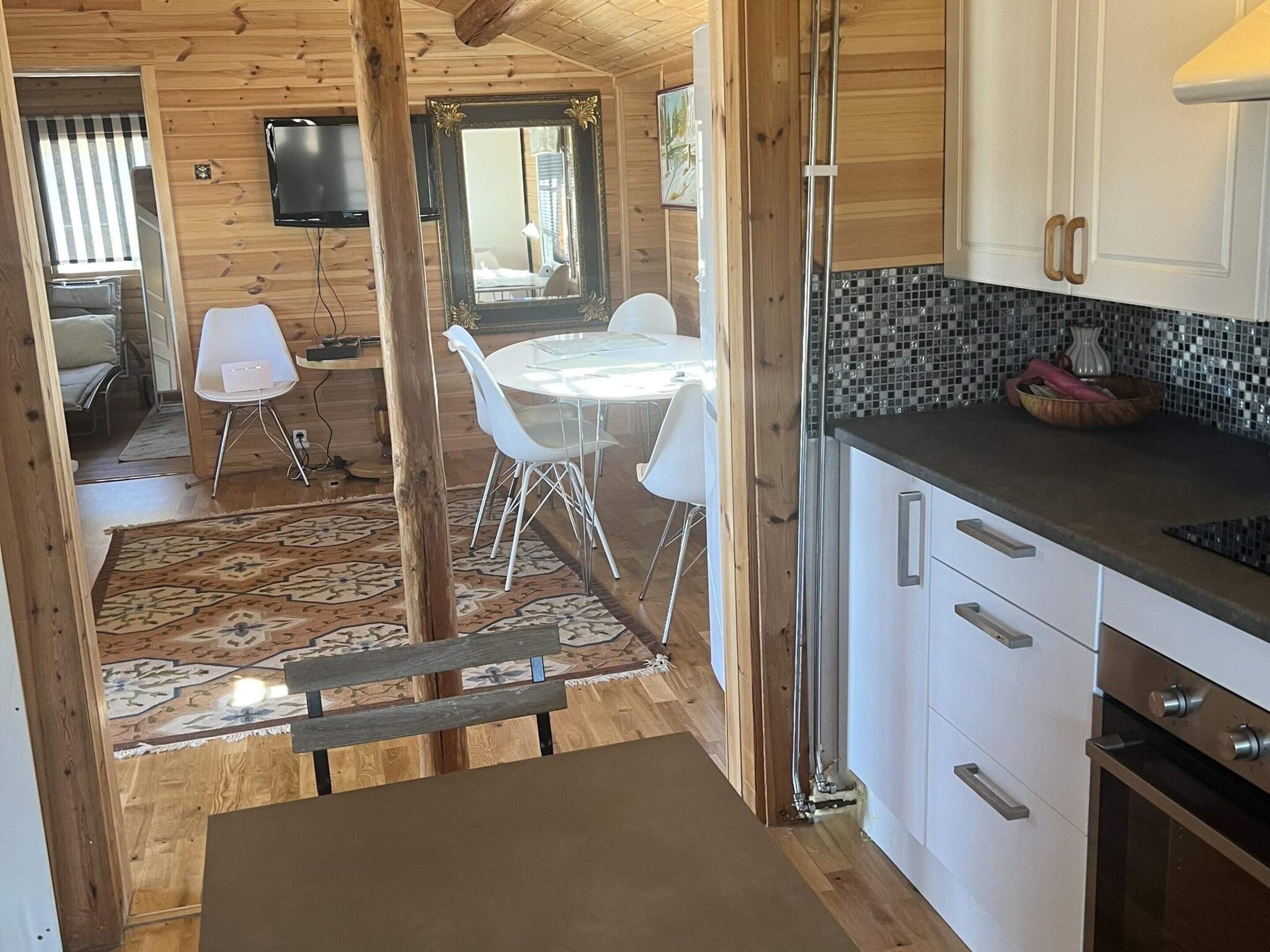 A wooden interior with a dining area, kitchen, and a television mounted on the wall.
