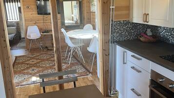A wooden interior with a dining area, kitchen, and a television mounted on the wall.