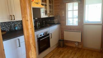 A kitchen with wooden cabinets, a stove, a sink, and a window.