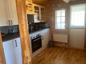 A kitchen with wooden cabinets, a stove, a sink, and a window. - 4 Star Holiday Home in Kil (Kil)
