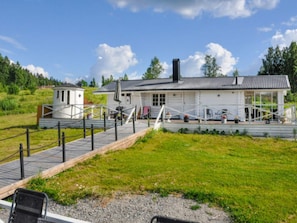 A house with a porch, a small attached structure, and a paved pathway leading to the entrance.