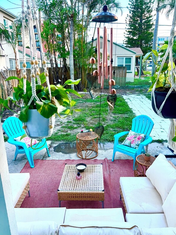 A patio area with outdoor seating, a hanging plant, and a decorative wind chime.