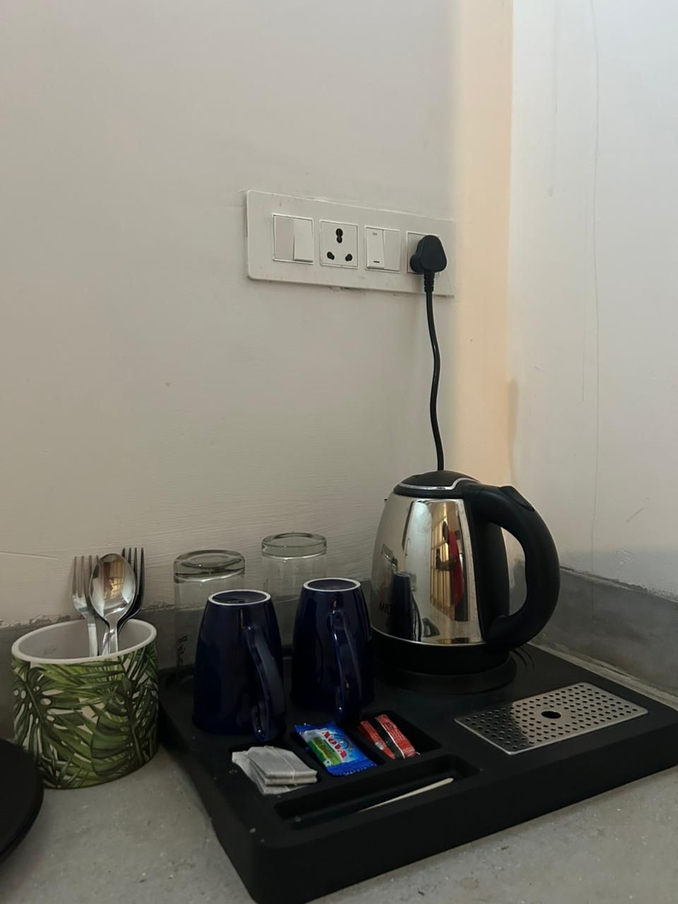 Una cocina con tetera, tazas, cuchara y una bandeja.