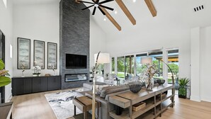 Ein modernes Wohnzimmer mit Kamin, großen Fenstern und Blick ins Freie.
