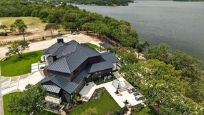 Ein modernes Haus mit einer großen Terrasse, einem Swimmingpool und Seeblick.