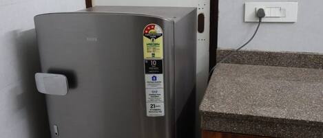 A compact refrigerator with a digital display, a power outlet, and a granite countertop.