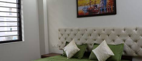 Un dormitorio con cama, aire acondicionado, ventana con persianas y un cuadro en la pared.