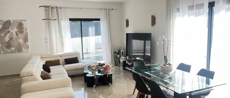 Un soggiorno moderno con un tavolo da pranzo in vetro, un divano e una TV.