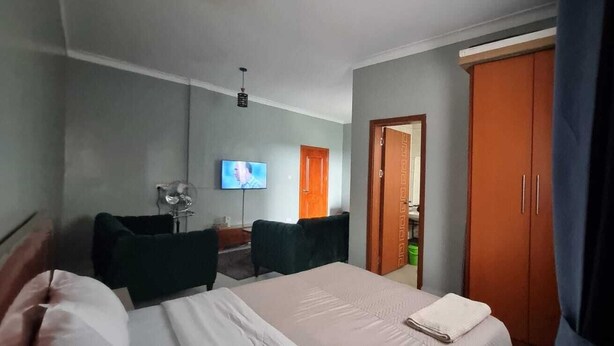 Ein Hotelzimmer mit Bett, Schreibtisch, Stuhl, Fernseher und Kleiderschrank.