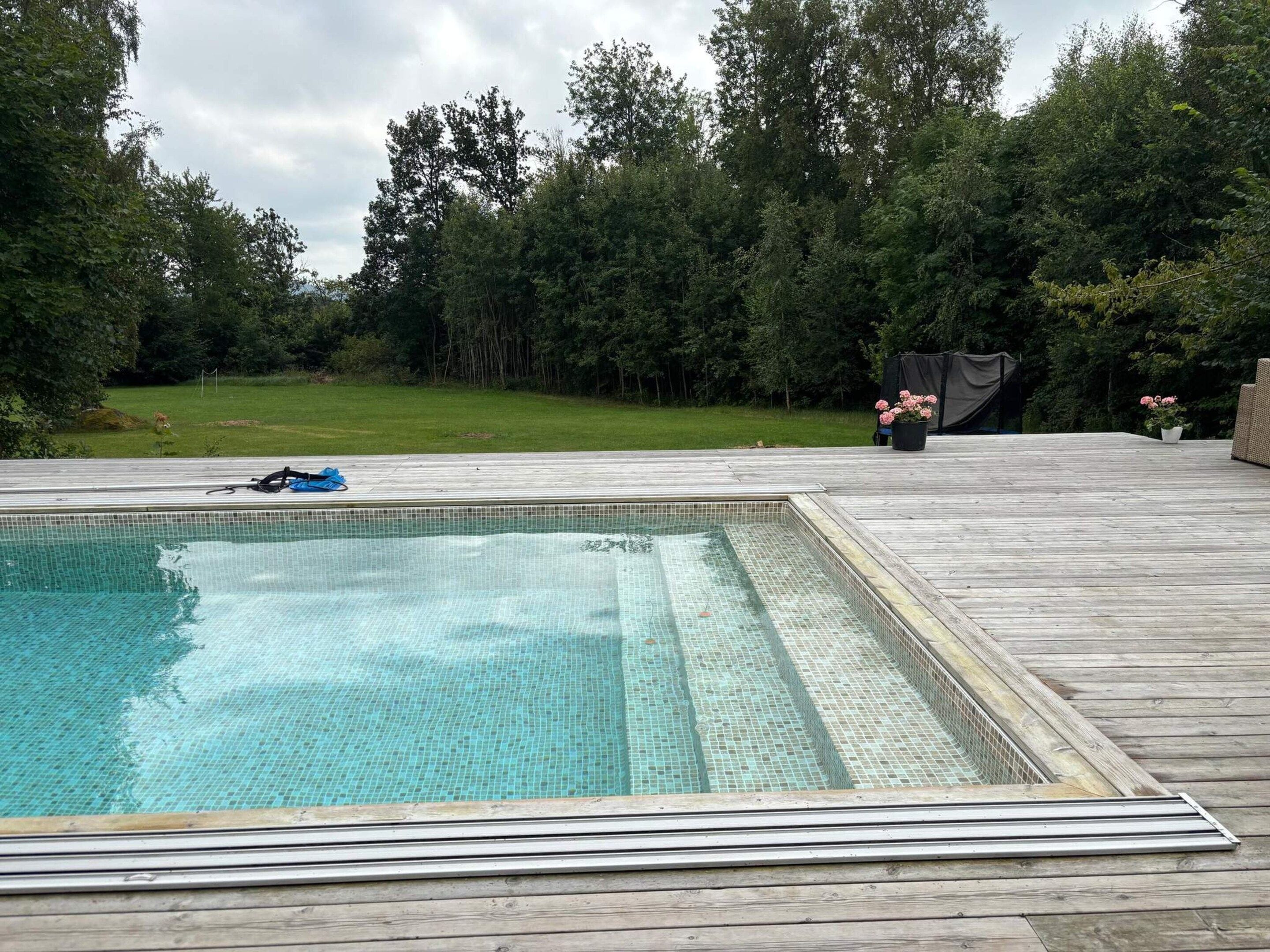 Une piscine entourée d’une terrasse en bois.