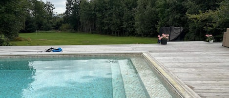A swimming pool with a wooden deck surrounding it.