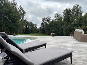 A poolside area with lounge chairs and a wooden deck. - 5 Star Holiday Home in Ugglarp (Sloinge)