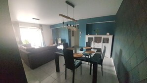 A dining area with a table and chairs, a sofa, and a kitchen area with cabinets and a countertop.
