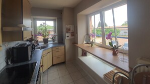 A kitchen with a window, cabinets, a microwave, and a sink.