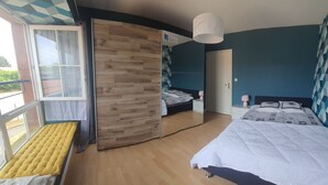 A bedroom with a bed, a bedside table, a nightstand, a window, and a door.