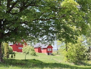 A red house with a sloped roof, surrounded by lush green trees and grass. - 4 Person Holiday Home in Ullared (Ullared)