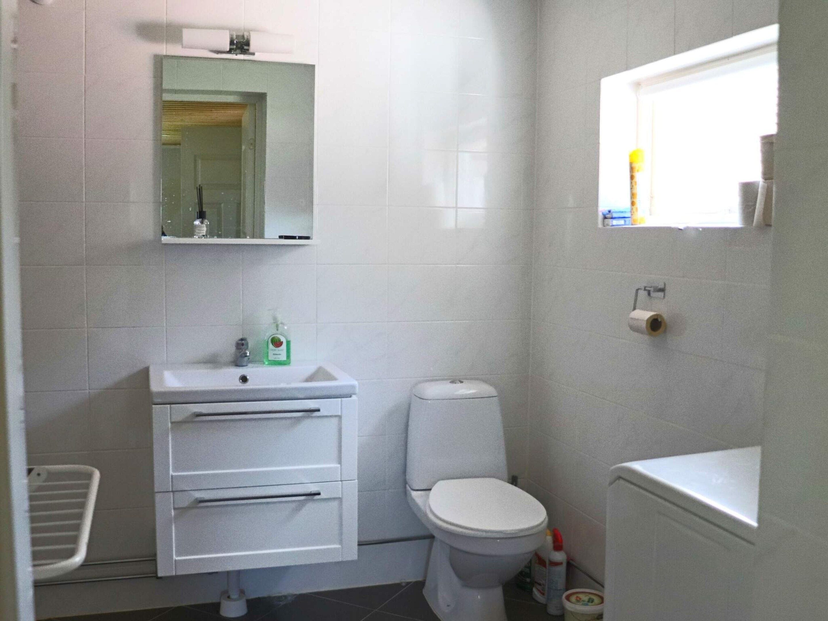 Une petite salle de bain propre, équipée de toilettes, d’un lavabo et d’un miroir.