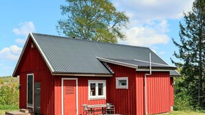 A red single-story building with a sloped roof, a small porch, and a table with chairs. - 4 Person Holiday Home in Ullared (Ullared)
